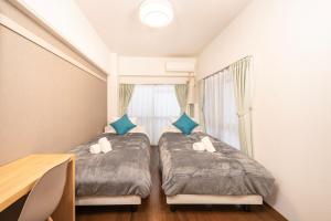 two beds in a small room with a window at CS Residence Chiba in Chiba
