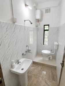 a white bathroom with a sink and a toilet at Sai Vatika Salbari Stays in Siliguri