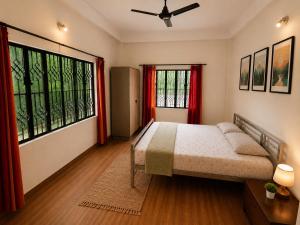 a bedroom with a bed and two large windows at Sai Vatika Salbari Stays in Siliguri