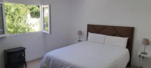 a white bedroom with a bed and a window at VILLA La TOSCA in Vega de San Mateo
