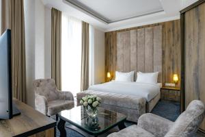 a hotel room with a bed and a table and chairs at Ramada by Wyndham Shymkent in Shymkent +113 photos