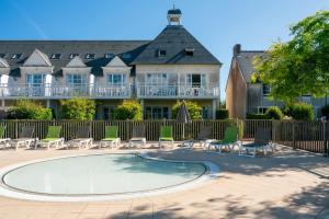 a pool in front of a house with chairs and a fence at Résidence Pierre & Vacances le Green Beach in Port-en-Bessin-Huppain
