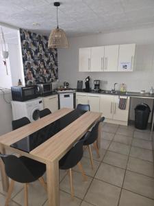 a kitchen with a wooden table and chairs at Un petit coin de paradis in Gavarret