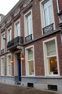 a red brick building with white windows and a blue door at The Hamptons Boutique B&B in Ghent