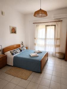 a bedroom with a bed with a blue comforter and a window at Pilgrimos Apartments in Ierissos