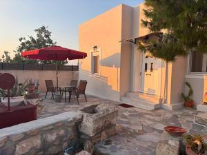 a patio with an umbrella and a table and chairs at Mitsakos Golden Villa in Egina