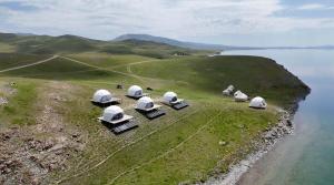 a group of observatories sitting on a hill near the water at Son-Köl Glamping in Song-Kul +40 photos