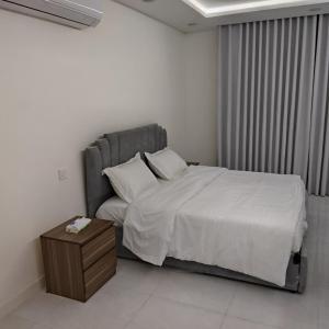 a bedroom with a large bed and a night stand at شقق غرفتين جديدة واسعة in Musaylah +4 photos