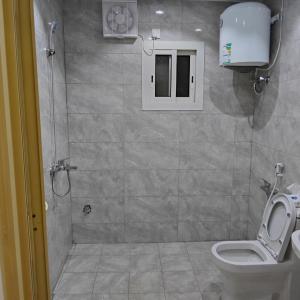 a bathroom with a shower with a toilet and a window at شقق غرفتين جديدة واسعة in Musaylah