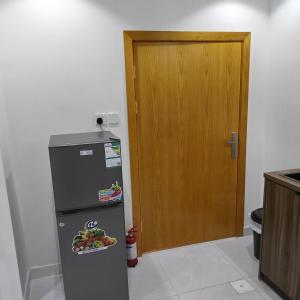 a kitchen with a refrigerator and a wooden door at شقق غرفتين جديدة واسعة in Musaylah