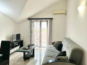 a living room with a couch and a tv at SeaSide Holiday Apartment in Bijela