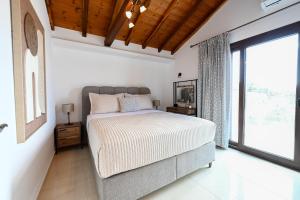 a bedroom with a bed and a large window at Villa Emerald Diamond in Kolios