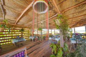a dining room with tables and chairs and a chandelier at Kizingo Beach Eco Lodge in Lamu