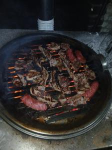 a pan filled with meat cooking on a grill at Mirjana Guesthouse in Pukë