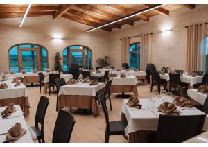 a restaurant with white tables and chairs and windows at Agriturismo Tenuta Santarcangelo in Scanzano
