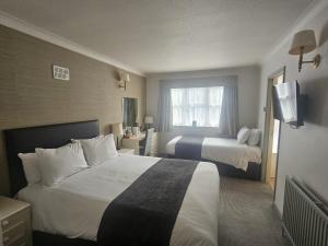 a hotel room with two beds and a window at Millers Hotel by Greene King Inns in Sibson