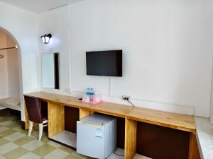 a room with a wooden desk with a tv on the wall at S2S Queen Trang Hotel in Trang