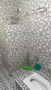 a bathroom with a toilet in a tiled floor at Alpine Adventures Guest House Gurez in Gurais