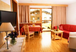 a living room with a red couch and a table at Biopension Alpenheim inkl SuperSommerCard in Fiss