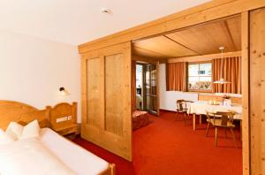 a hotel room with a bed and a dining room at Biopension Alpenheim inkl SuperSommerCard in Fiss