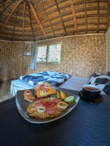 a plate with food on a table with two beds at Asaro Mudman Cultural Lodge in Goroka