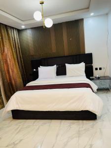a bedroom with a large bed with a black headboard at Soilsmart haven in Abuja