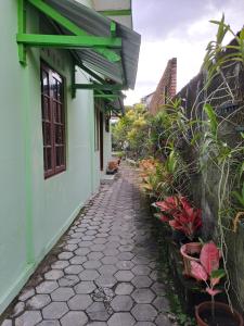 a cobblestone walkway next to a green building with plants at Omah 365 Homestay in Yogyakarta