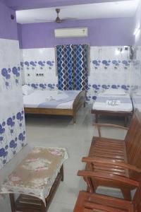 a room with two beds and a bench in it at Hotel Eswara Temple Stay in Kumbakonam +2 photos