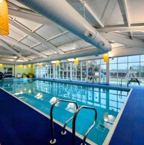 a large swimming pool with blue water in a building at The Joanack Breeze in Withernsea