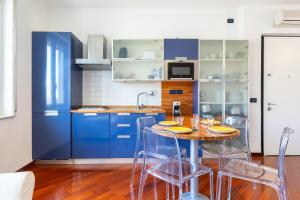 a kitchen with blue cabinets and a table with chairs at Hostdomus - Brezza Marina House in Alassio