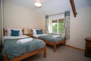 two beds in a room with a window at The Barn - Old Mill Cottages in Ilfracombe