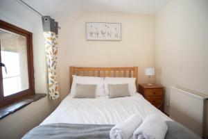 a bedroom with a bed with white sheets and a window at The Barn - Old Mill Cottages in Ilfracombe +26 photos