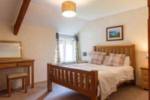 a bedroom with a bed and a desk and a mirror at The Barn - Old Mill Cottages in Ilfracombe