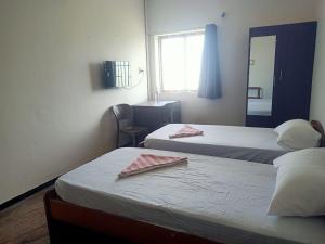 a hotel room with two beds and a mirror at jambu's residence in Karūr