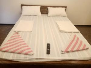 a bed with two pillows and a remote control on it at jambu's residence in Karūr +5 photos
