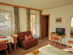 a hotel room with a bed and a chair and a television at Balthasarhof, Haus in Finkenberg