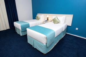 two beds in a hotel room with blue walls at فندق برهان الهدى in Mecca +22 photos