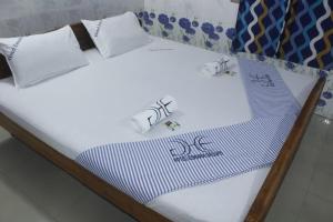 a bed with white sheets and pillows on it at Hotel Eswara Temple Stay in Kumbakonam