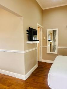 a bedroom with a bed and a tv on a wall at Hidden Villas Guesthouse in East London