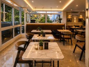 a restaurant with tables and chairs and windows at Hotel Rudransh in Rānchī