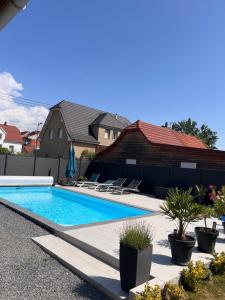 a swimming pool in a yard with chairs and a house at Chambre d hôtes chez Carol et Patrick in Gundershoffen