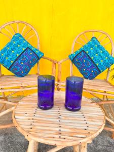 a wooden table with two chairs and two blue glasses at Khangadelic Kilifi in Kilifi