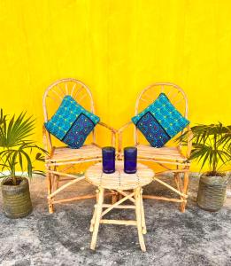 two chairs with blue pillows on them next to a yellow wall at Khangadelic Kilifi in Kilifi
