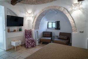 a room with a bed and two chairs and a tv at I Trulli di Anna in Locorotondo