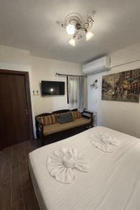 a bedroom with a white bed and a couch at Psichro Apartments Zeus in Magoulás