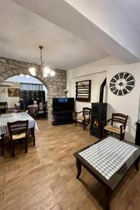 a living room with a table and a clock on the wall at Psichro Apartments Zeus in Magoulás