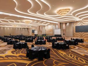 a ballroom with tables and chairs and a projection screen at Grand Mercure Malang Mirama in Malang +69 photos