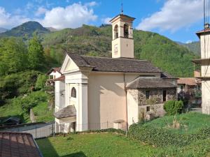 a small white church with a clock tower on a hill at Casa Margherita in Forno