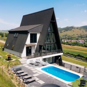 a house with a black roof and a swimming pool at Vicanto A frame Bucovina in Gura Humorului