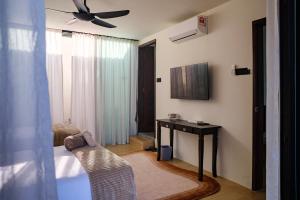 a bedroom with a bed and a table and a ceiling fan at Padé Langkawi in Ulu Melaka